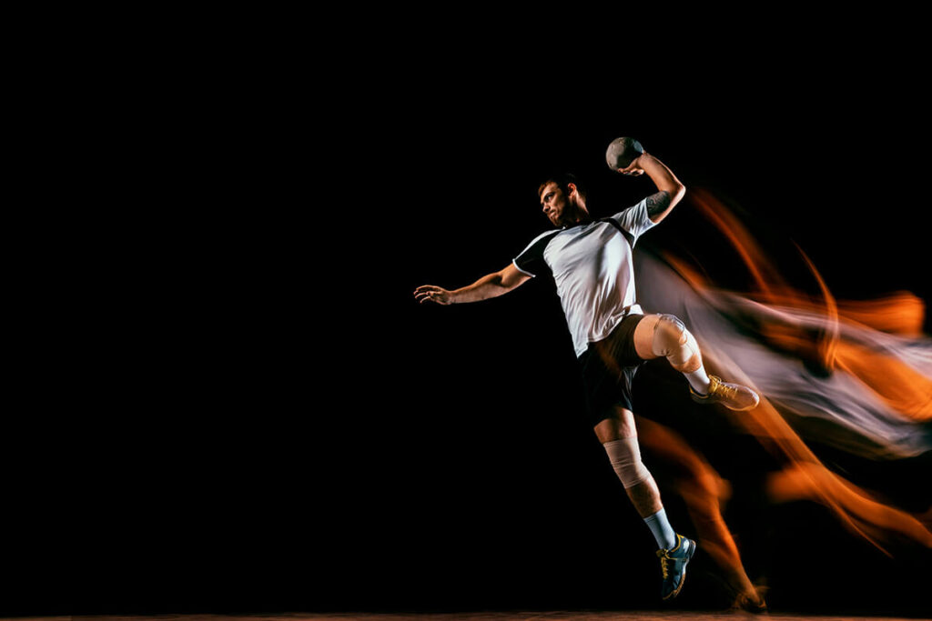 un jugador de handball a punto de lanzar el balón en un fondo en negro y con efectos de movimiento