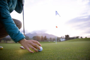una persona colocando su pelota en el green del campo de golf, un espacio desafiante