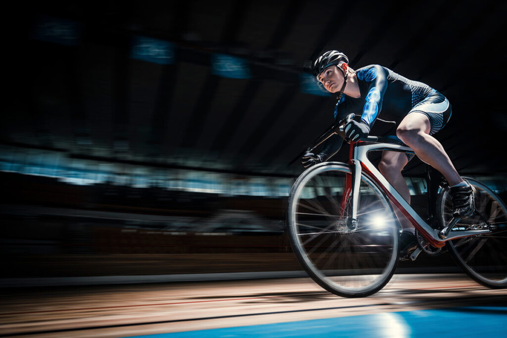 Un ciclista participando en una competencia de ciclismo de pista en un velódromo.