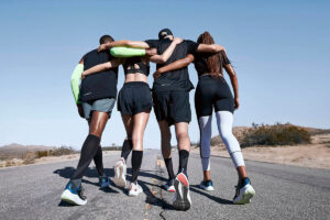 un grupo de amigos y amigas después de un entrenamiento apoyándose mientras usan productos de Nike running