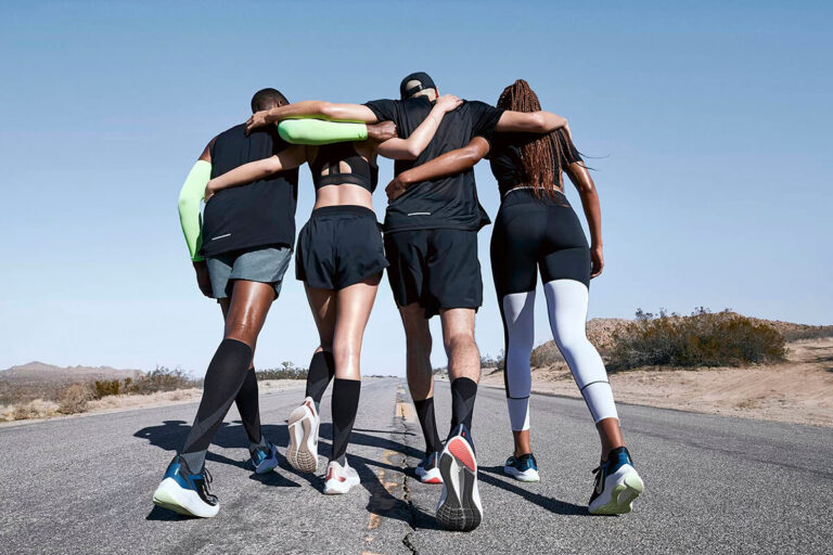 un grupo de amigos y amigas después de un entrenamiento apoyándose mientras usan productos de Nike running