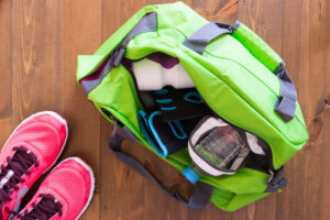 Una maleta deportiva que guarda la ropa fitness y unos tenis a lado