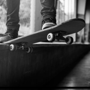 foto en blanco y negro de una patineta y unos tenis al borde de una rampa