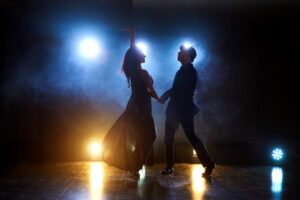 Dos personas bailando danzón en un escenario a contraluz. Fotografía por Standret.