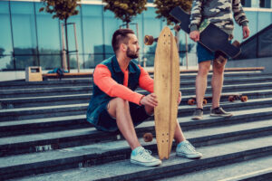 Un chico sosteniendo su longboard a diferencia de una patineta de skate